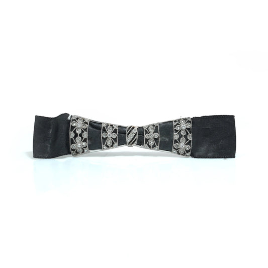 A floral design diamond and platinum bow brooch with a black ribbon