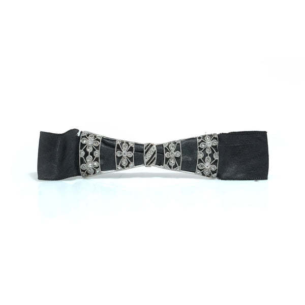 A floral design diamond and platinum bow brooch with a black ribbon