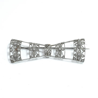 A floral design diamond and platinum bow brooch