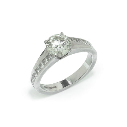 A brilliant cut diamond solitaire ring with square diamond set shoulders, in platinum