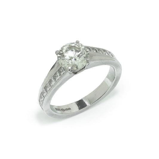 A brilliant cut diamond solitaire ring with square diamond set shoulders, in platinum
