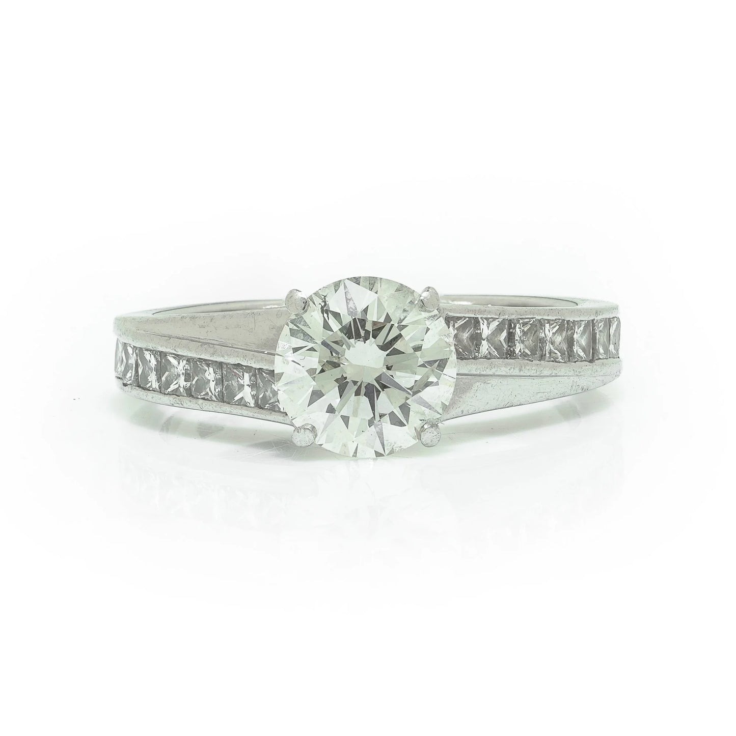 A brilliant cut diamond solitaire ring with square diamond set shoulders, in platinum