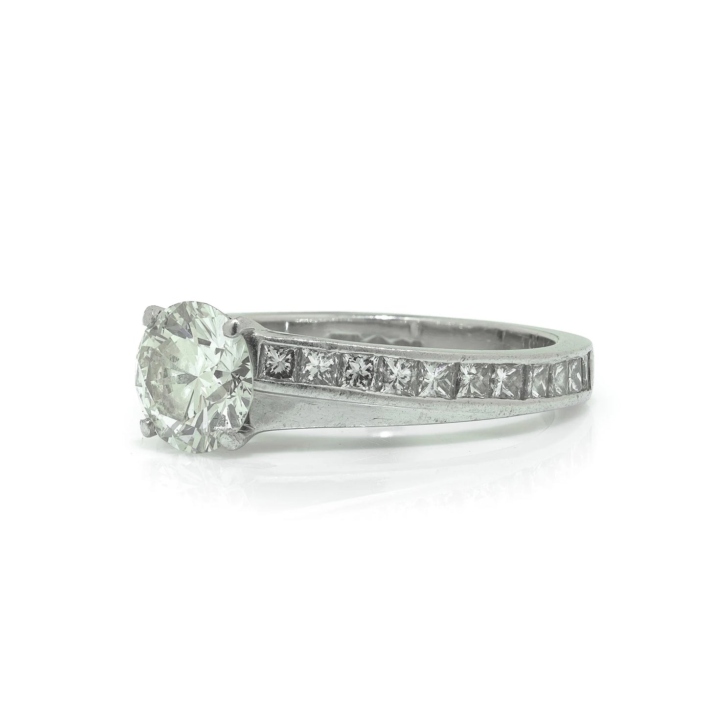 A brilliant cut diamond solitaire ring with square diamond set shoulders, in platinum