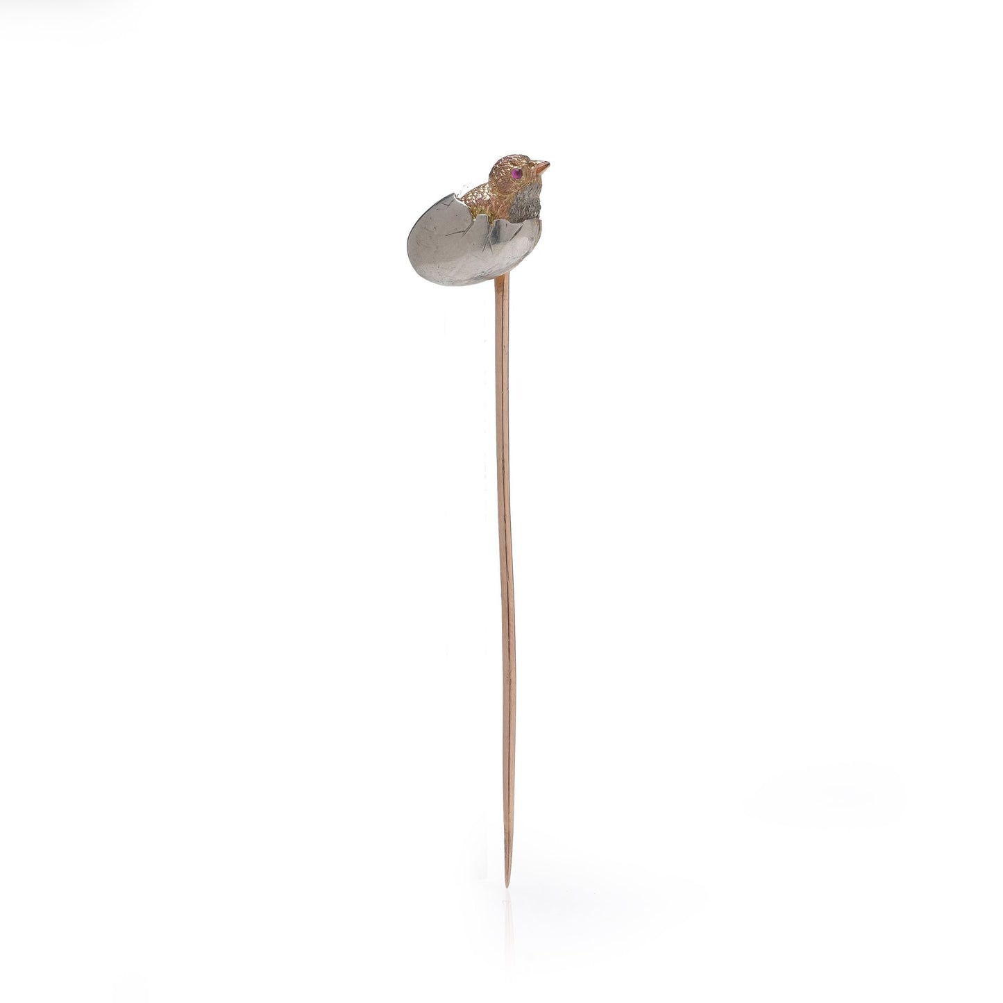 A stick pin depicting a chick hatching from an egg, in gold and silver