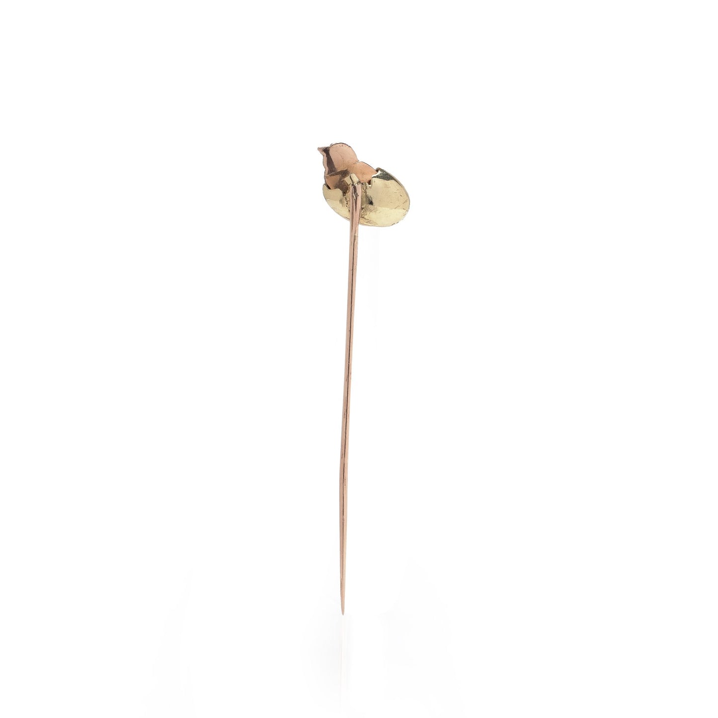 A stick pin depicting a chick hatching from an egg, in gold and silver