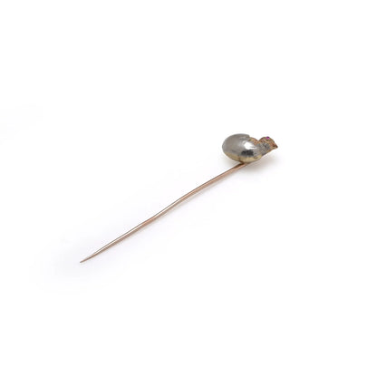 A stick pin depicting a chick hatching from an egg, in gold and silver