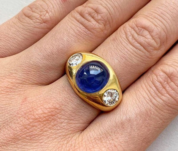 Vintage 18.96ct Ceylon Sapphire, Diamond and 18ct Gold Ring; oval cabochon Ceylon sapphire flanked by round brilliant cut diamonds, Germany, Circa 1980.