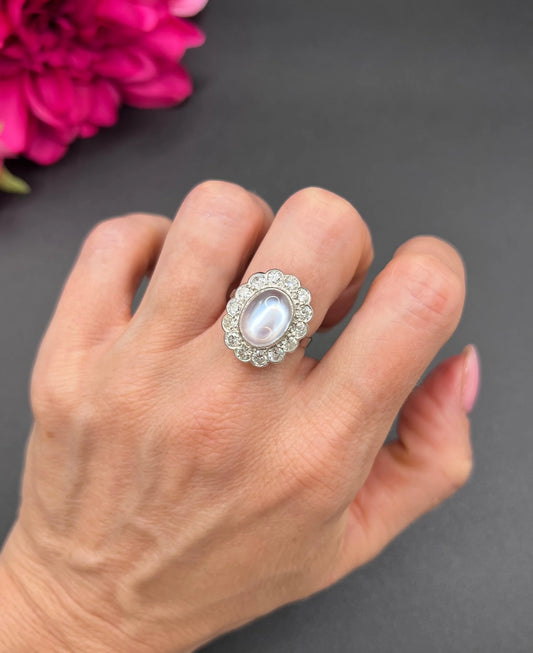 A cabochon moonstone and diamond oval cluster ring in platinum, modelled on a hand