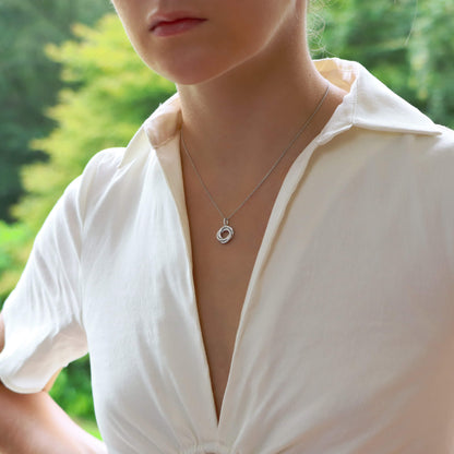 A white gold diamond set open circle pendant on a white gold chain, modelled by a woman wearing a white shirt