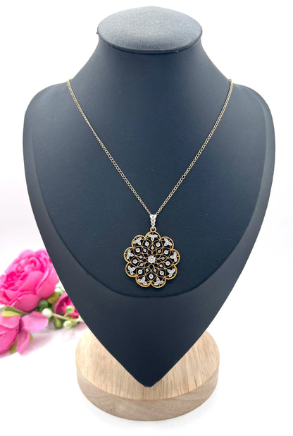 A floral openwork diamond pendant in gold and platinum, with a chain, on a black jewellery bust