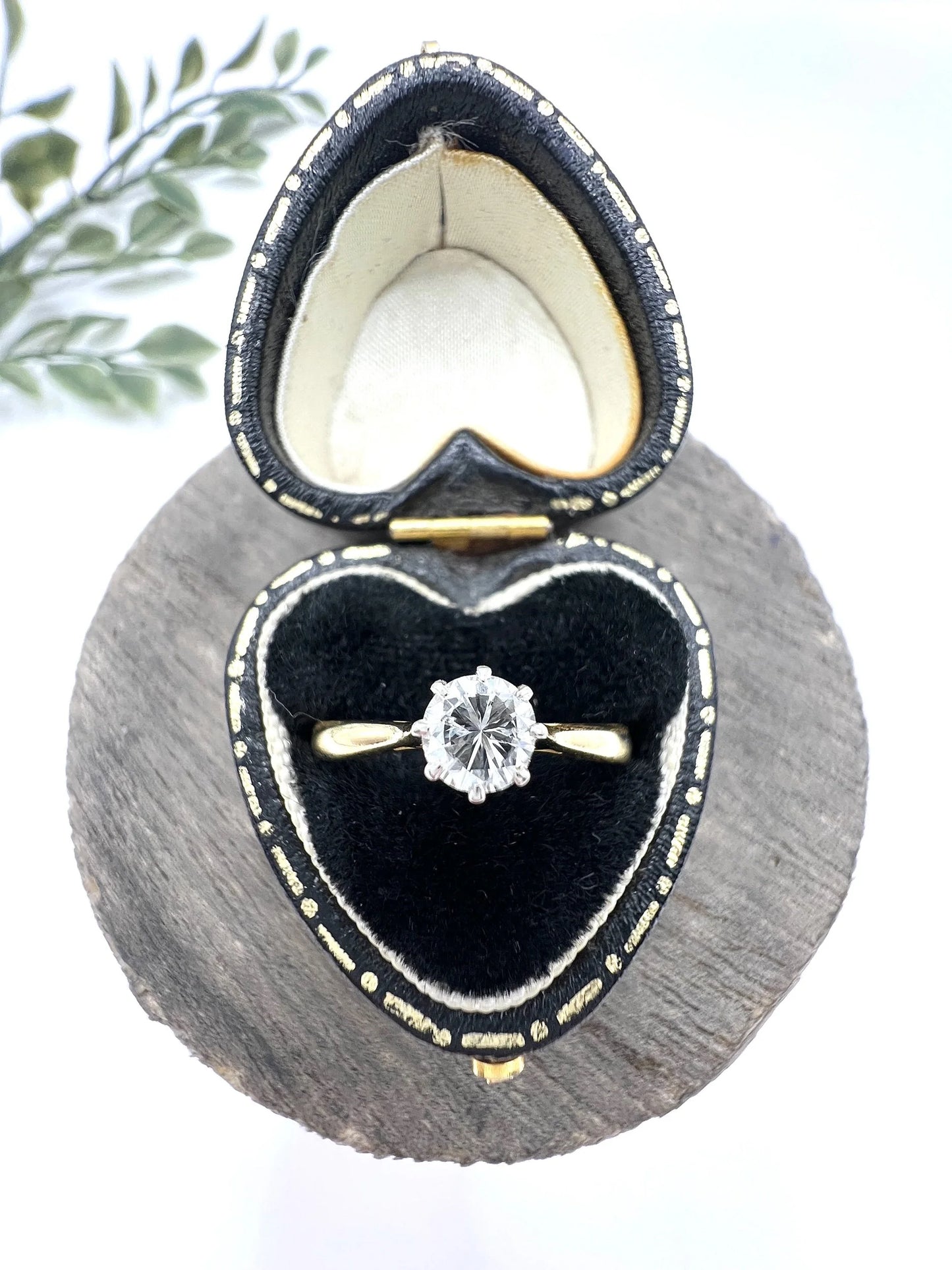 A single stone brilliant cut diamond ring claw set in platinum and yellow gold, in a heart-shaped ring box