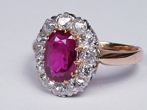 Antique Victorian Ruby and Diamond Oval Cluster Ring; featuring a 1.15 carat oval faceted ruby encompassed by 1.20cts sparkling diamonds, on a rose gold shank. English, Circa 1890