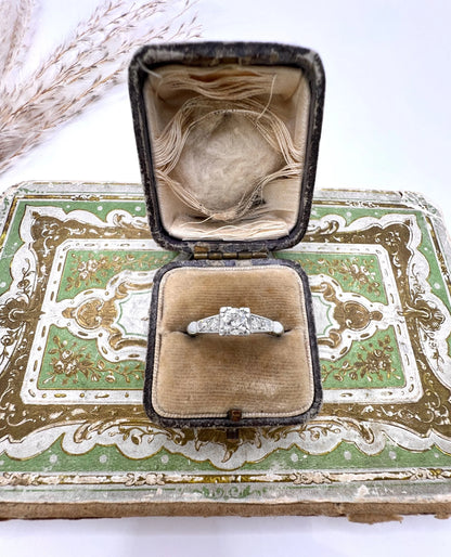 A solitaire diamond ring in platinum, with diamond set shoulders, in a ring box