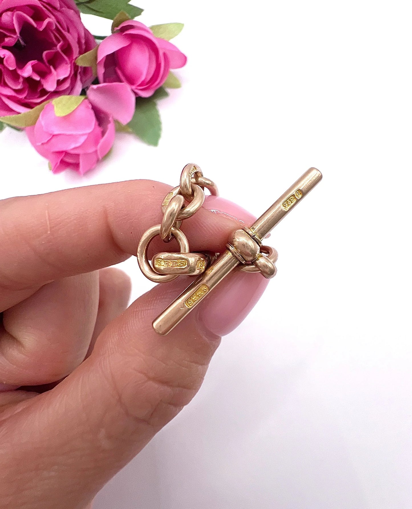 A rose gold t-bar with stamps, held in a hand