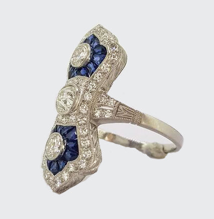Art Deco Style Sapphire and Diamond Navette Panel Ring; navette-shaped ring set with brilliant-cut diamonds and calibre-cut sapphires. Mounted in platinum.