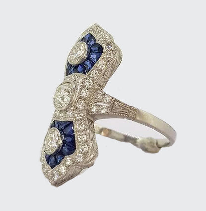 Art Deco Style Sapphire and Diamond Navette Panel Ring; navette-shaped ring set with brilliant-cut diamonds and calibre-cut sapphires. Mounted in platinum.