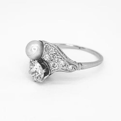 Belle Epoque Natural Pearl and Old Cut Diamond Ring; featuring an old cut diamond and grey natural pearl, diamond encrusted shoulders. Mounted in platinum with a pierced scrolled under-gallery