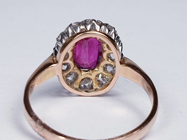 Antique Victorian Ruby and Diamond Oval Cluster Ring; featuring a 1.15 carat oval faceted ruby encompassed by 1.20cts sparkling diamonds, on a rose gold shank. English, Circa 1890