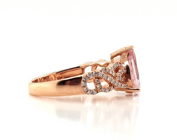 Pear Cut Morganite and Diamond Cluster Dress Ring; central 1.75 carat pear-shaped morganite flanked by 0.33cts diamond set overlapping waves and swirls, in 18ct rose gold