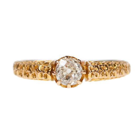 A yellow gold single stone diamond ring with a decorative shank