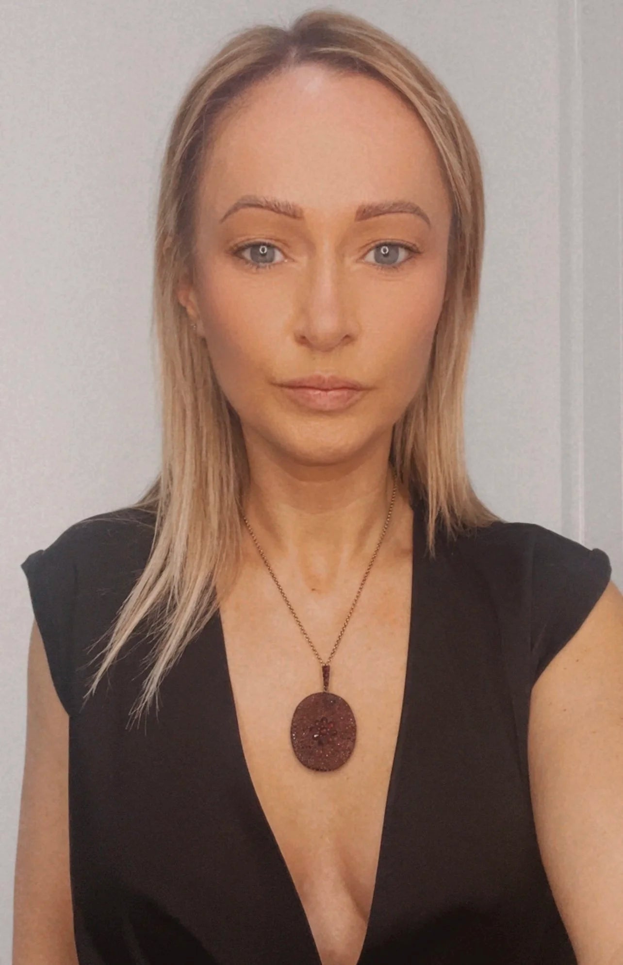 An antique oval locket encrusted with garnets, with a chain, modelled by a woman