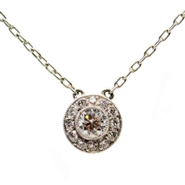 Vintage Art Deco Style Diamond and Platinum Cluster Pendant Necklace; a 0.25ct round brilliant cut diamond surrounded by a halo of diamonds, with chain.