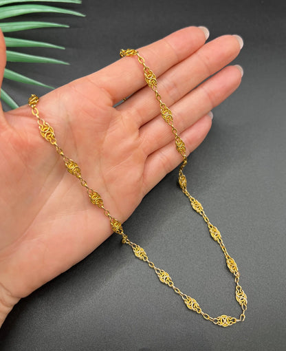 A yellow gold fancy link chain necklace, held in a hand