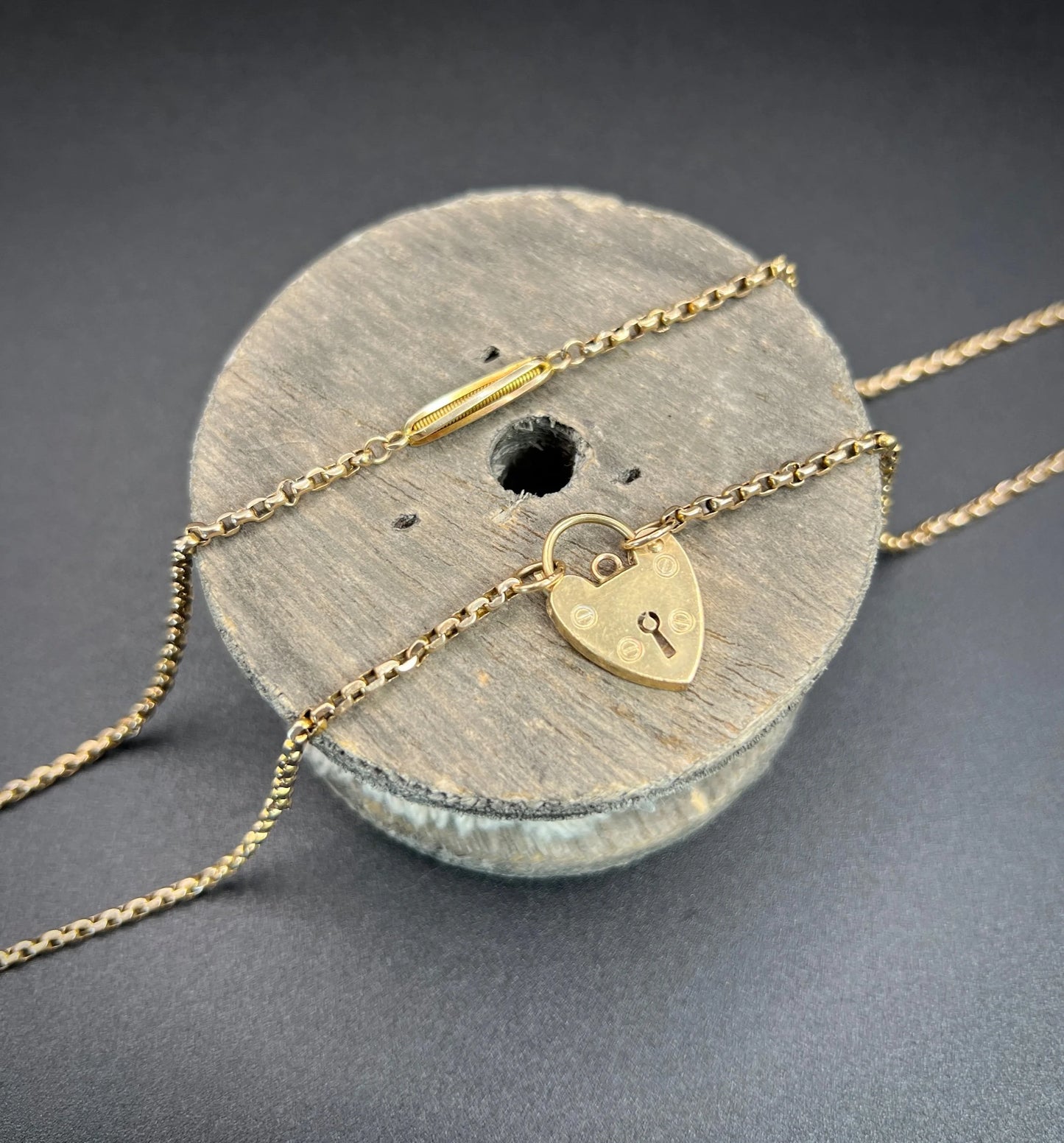 A yellow gold fancy link chain with a heart padlock