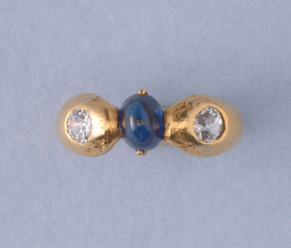 Art Deco Sapphire and Old Cut Diamond Snake Ring; two snake heads each set with an old cut diamond and holding a 1.60ct oval cabochon-cut sapphire between them, in platinum with later gilding. France, Circa 1920