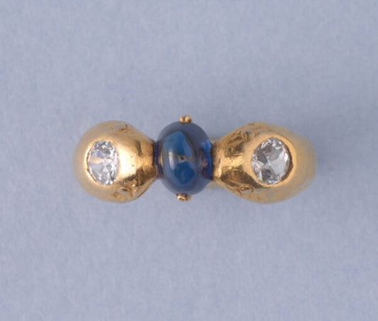 Art Deco Sapphire and Old Cut Diamond Snake Ring; two snake heads each set with an old cut diamond and holding a 1.60ct oval cabochon-cut sapphire between them, in platinum with later gilding. France, Circa 1920