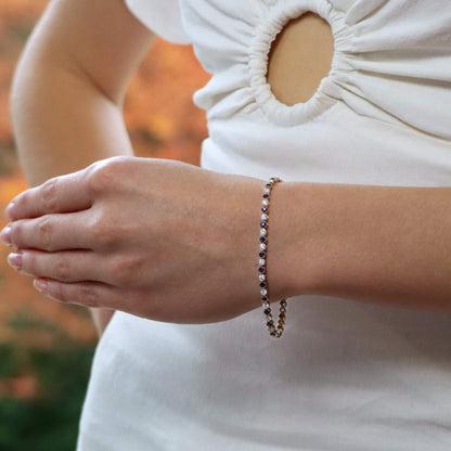 A sapphire and diamond line bracelet in yellow and white gold, modelled on the wrist of a woman wearing a white dress