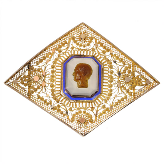 A yellow gold ornate openwork brooch with an agate cameo portrait in the centre, bordered with blue enamel