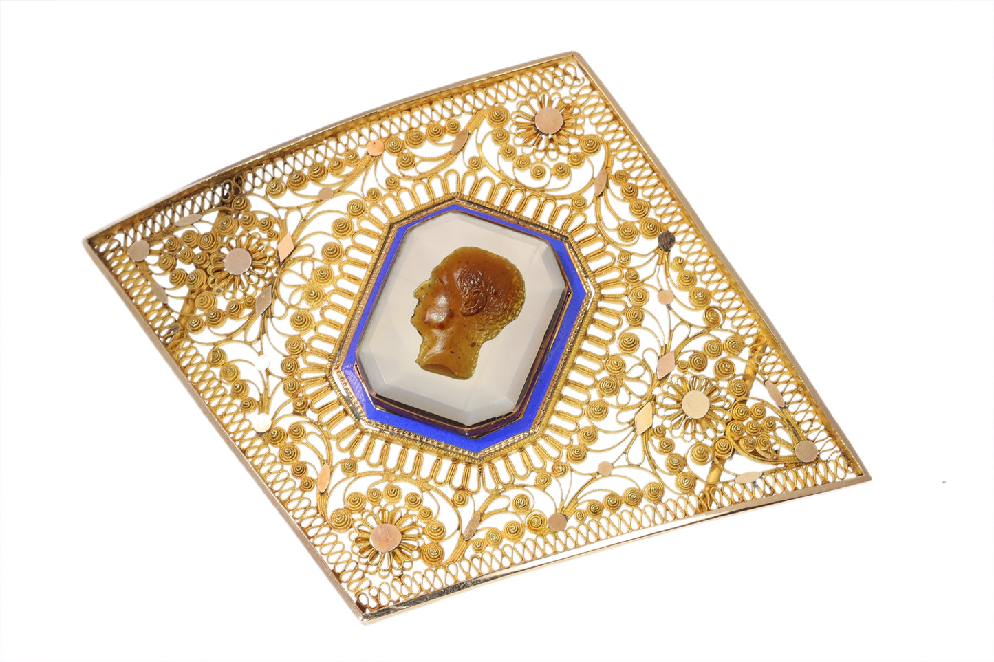 A yellow gold ornate openwork brooch with an agate cameo portrait in the centre, bordered with blue enamel