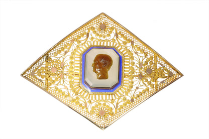 A yellow gold ornate openwork brooch with an agate cameo portrait in the centre, bordered with blue enamel