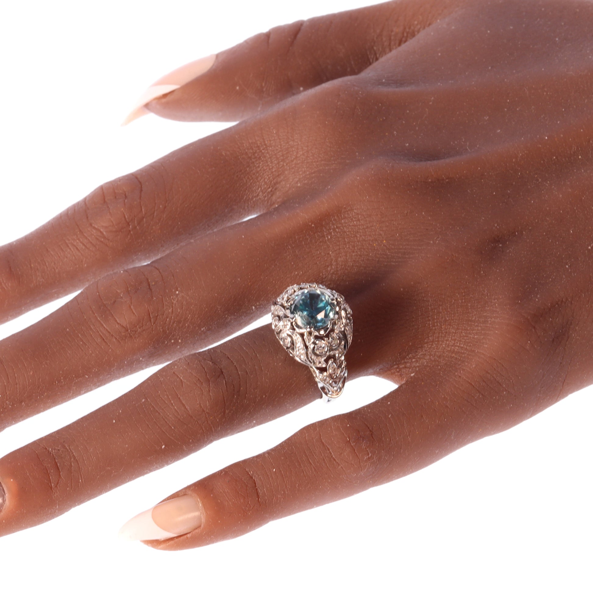 A round blue zircon and diamond openwork ring in platinum, modelled on a hand