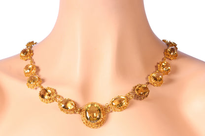 An intricate yellow gold necklace set with oval citrines in filigree mounts, modelled on a neck