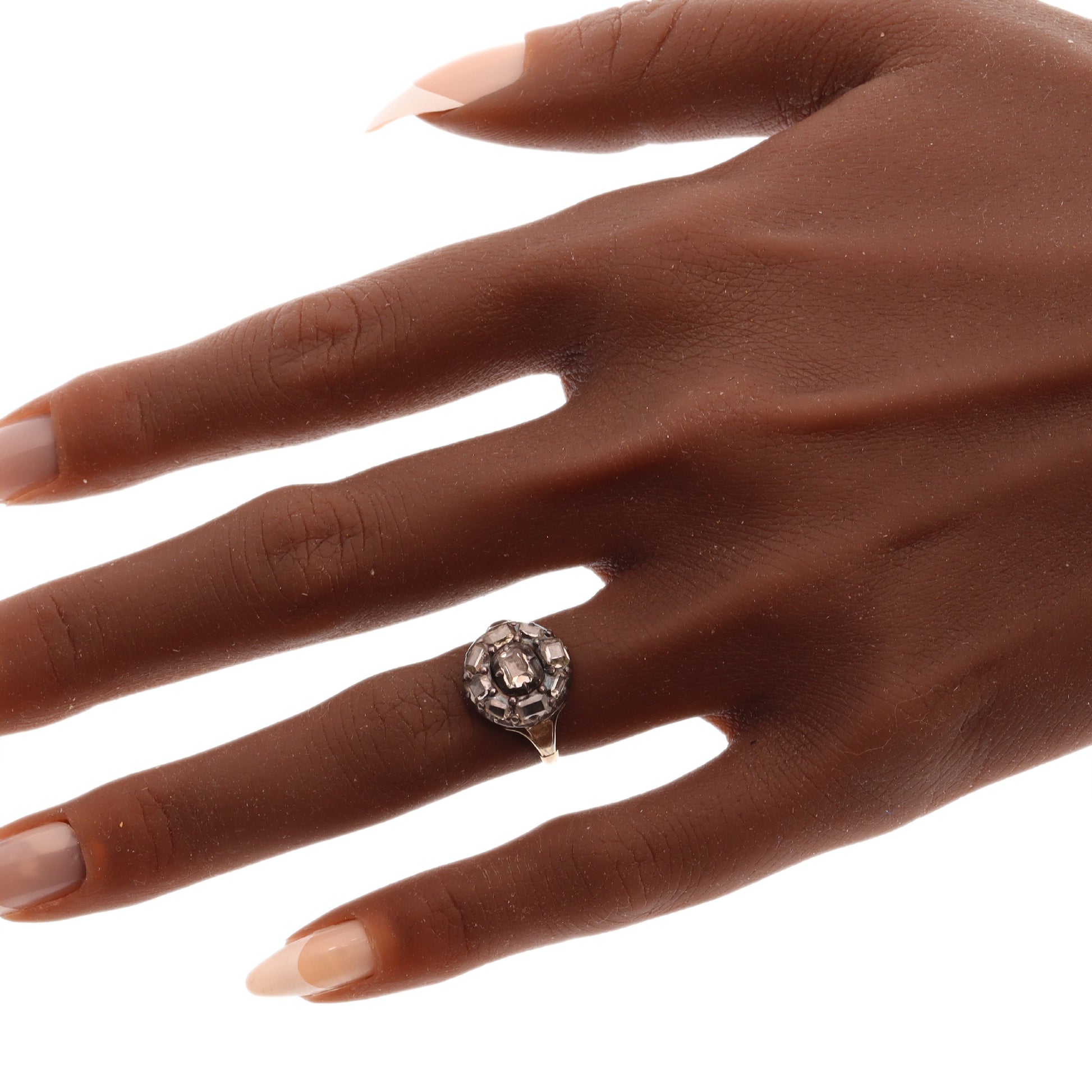 An antique circular cluster ring with table cut diamonds, in gold and silver, modelled on a hand