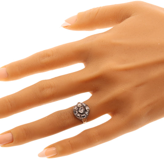 An antique circular cluster ring with table cut diamonds, in gold and silver, modelled on a hand