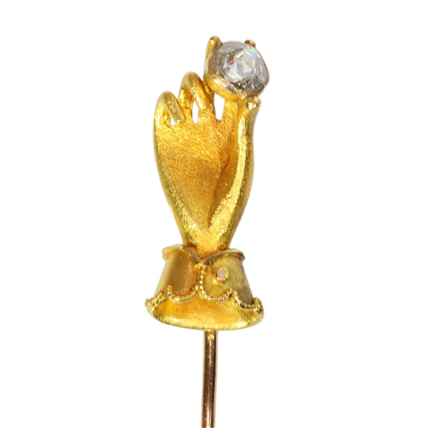 A yellow gold hand holding a diamond stick or tie pin
