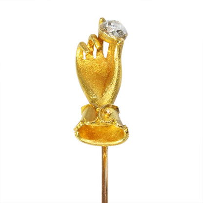 A yellow gold hand holding a diamond stick or tie pin