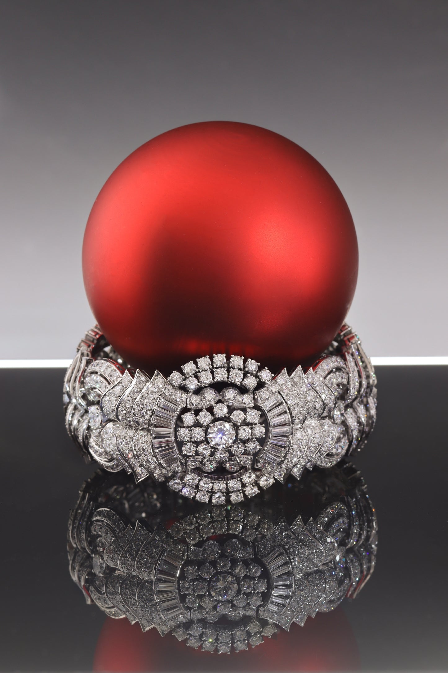 A fine diamond geometric bracelet in platinum, with a red bauble