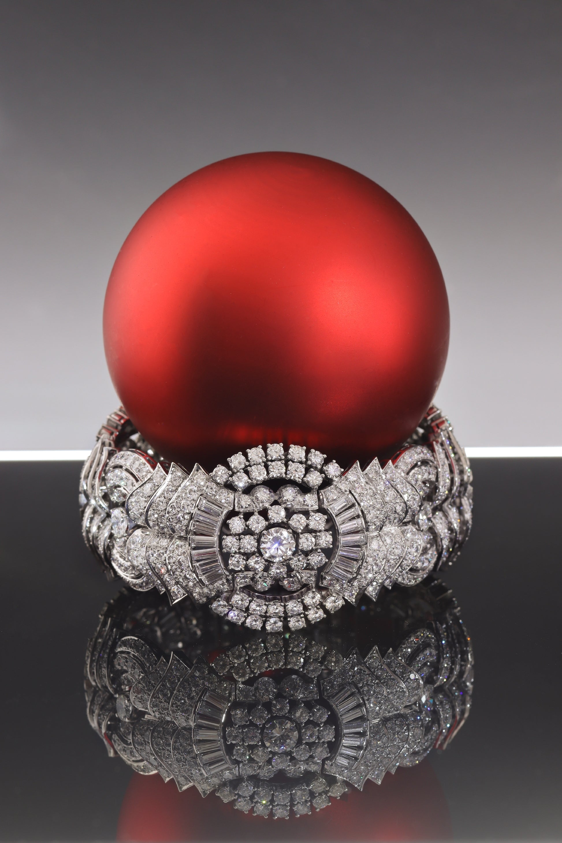 A fine diamond geometric bracelet in platinum, with a red bauble