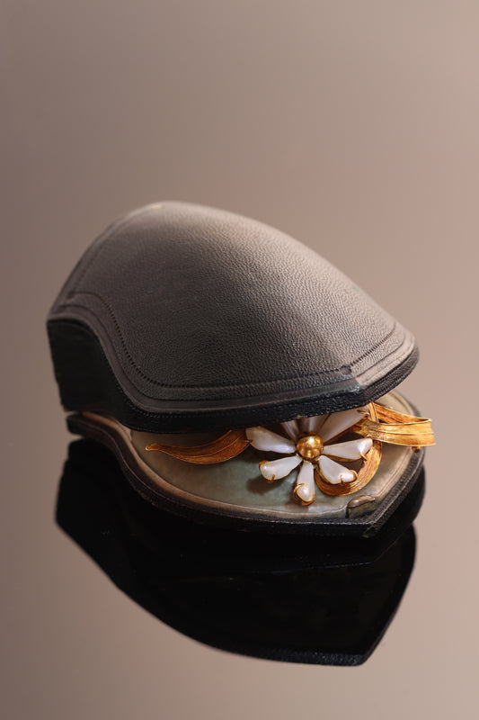 An antique yellow gold flower brooch with elongated white pearls, in an antique box
