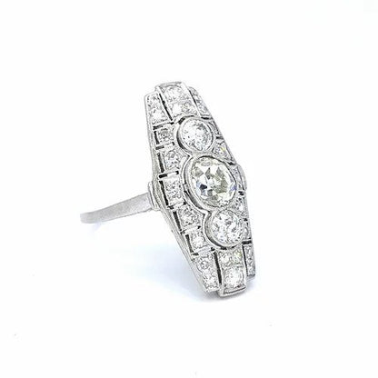 Art Deco Diamond and Platinum Three Stone Cluster Plaque Ring; featuring three brilliant cut diamonds in vertical formation surrounded by smaller circular diamonds, set in a pierced platinum mount with millegrain edging