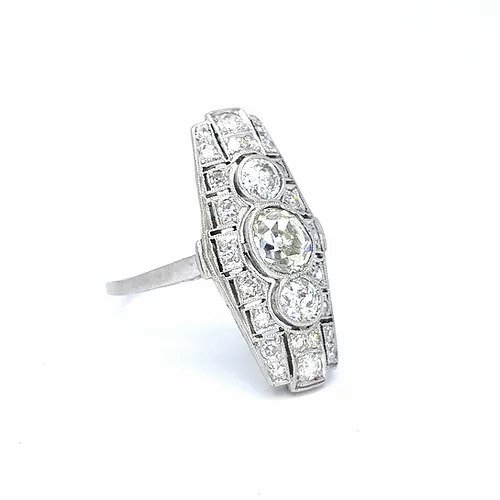 Art Deco Diamond and Platinum Three Stone Cluster Plaque Ring; featuring three brilliant cut diamonds in vertical formation surrounded by smaller circular diamonds, set in a pierced platinum mount with millegrain edging