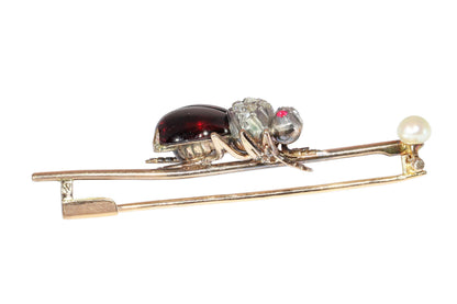 An antique gold bar brooch with a diamond, garnet and ruby set insect in the centre