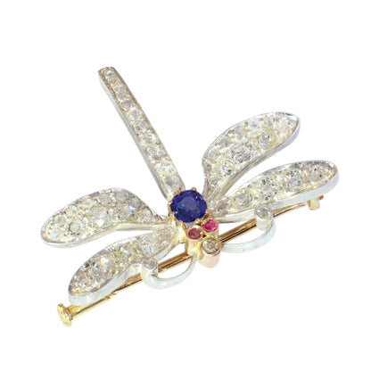A dragonfly shaped brooch with diamonds, two ruby eyes and a sapphire body