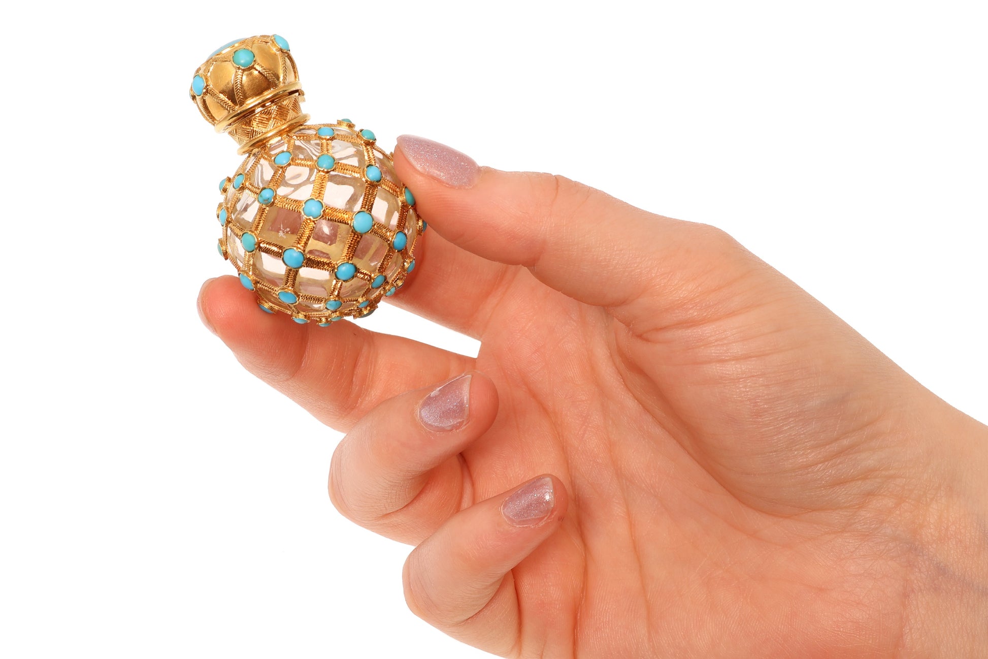 A yellow gold decorative perfume bottle with cabochon turquoise, held in a hand