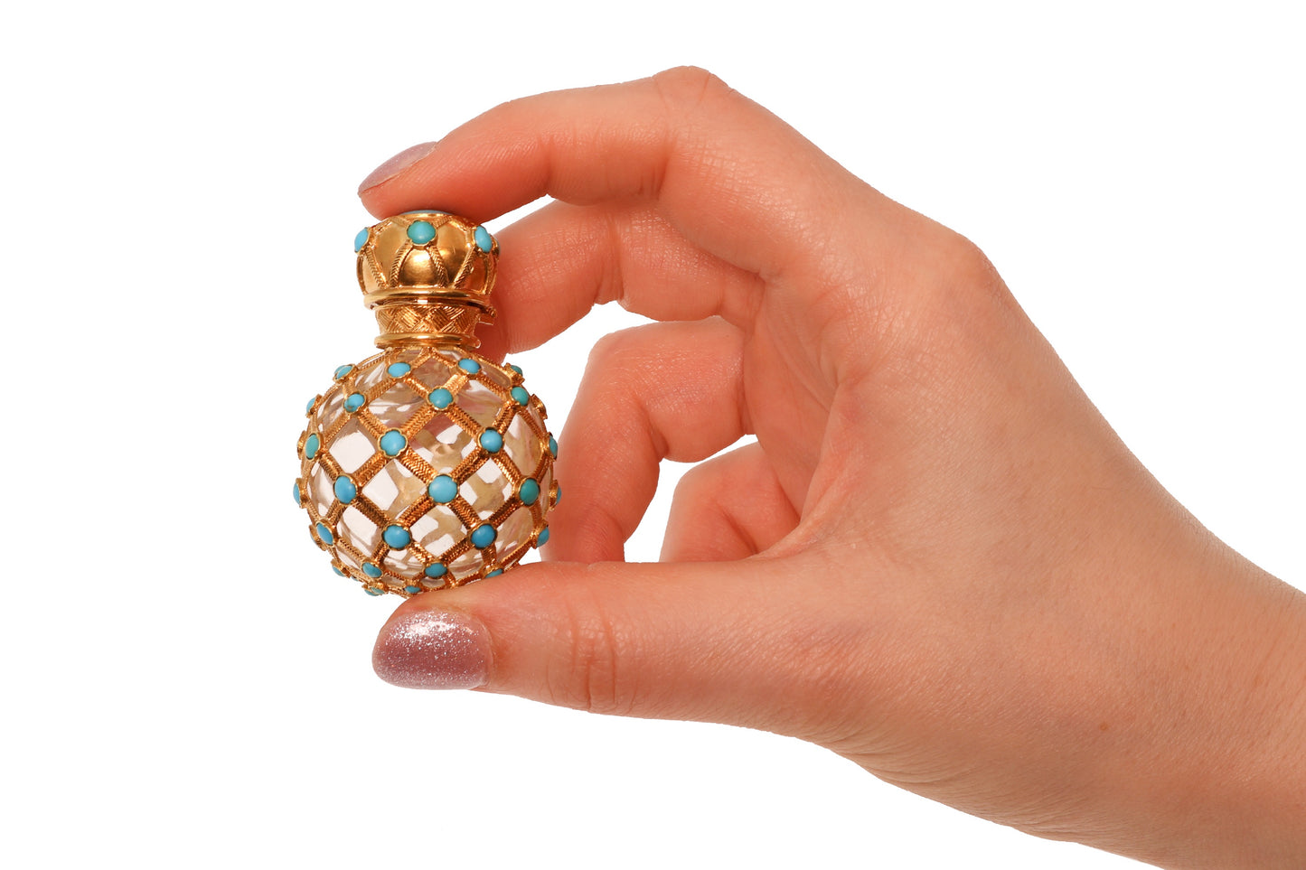 A yellow gold decorative perfume bottle with cabochon turquoise, held in a hand