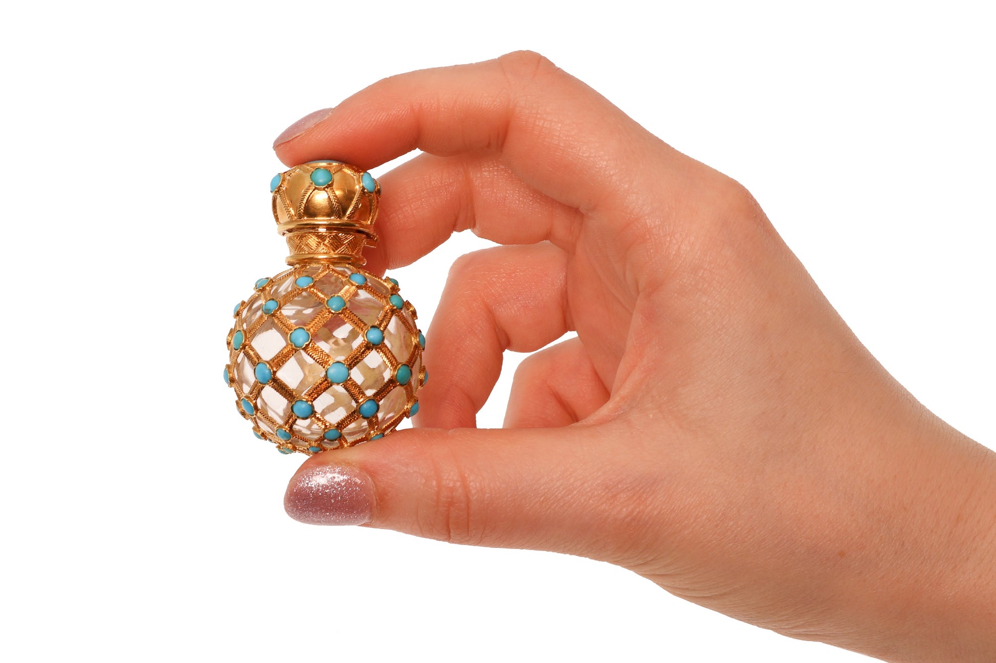 A yellow gold decorative perfume bottle with cabochon turquoise, held in a hand